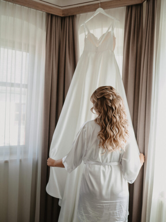 Birkenheide | Germany 2 Bride admiring her wedding gown at the window in Birkenheide